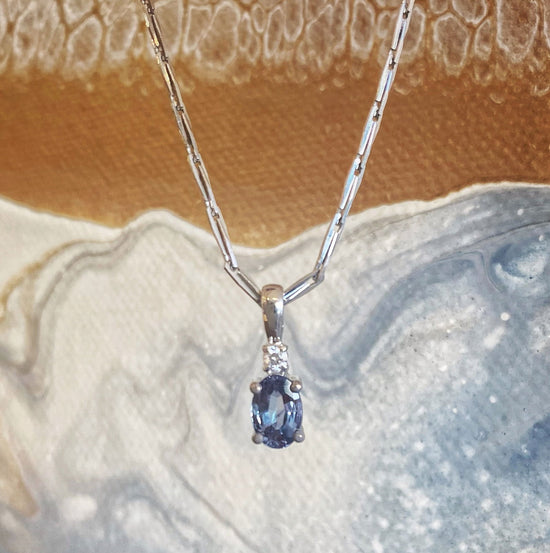 Photo of 14K White Gold Alexandrite and Diamond Pendant in a decorative scene, designed by , available at Plumb Gold & Plumb Silver