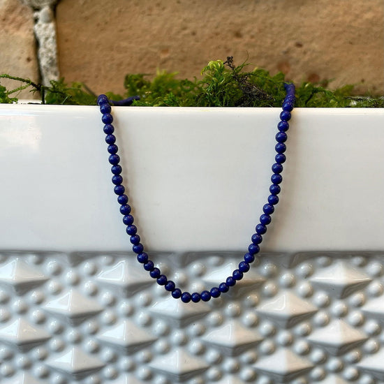 Photo of Beaded Lapis Necklace in a decorative scene, designed by , available at Plumb Gold & Plumb Silver