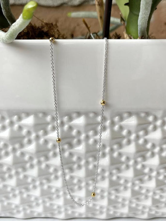 Photo of Beaded Station Necklace in a decorative scene, designed by , available at Plumb Gold & Plumb Silver