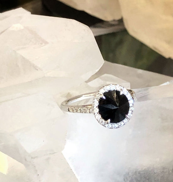 Photo of Black Spinel Diamond Halo Ring in White Gold in a decorative scene, designed by , available at Plumb Gold & Plumb Silver