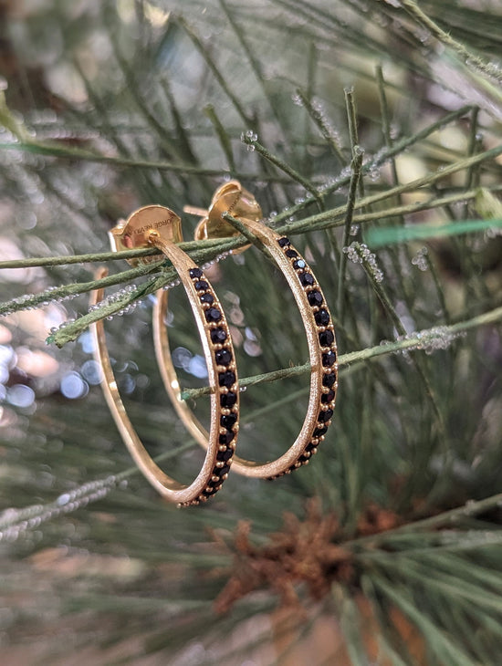 Photo of Black Spinel Hoop Post Earrings in a decorative scene, designed by , available at Plumb Gold & Plumb Silver