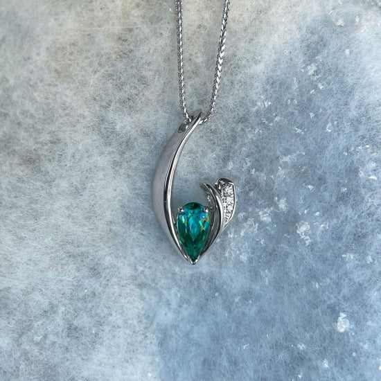 Photo of Blue-Green Tourmaline and Diamond Pendant in a decorative scene, designed by , available at Plumb Gold & Plumb Silver