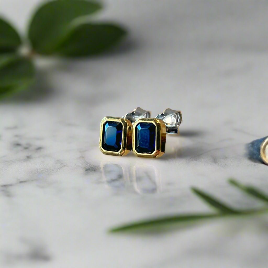 Photo of Blue Cubic Zirconia Studs in a decorative scene, designed by , available at Plumb Gold & Plumb Silver