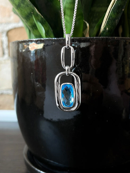 Photo of Blue Topaz Chain Link Pendant in a decorative scene, designed by , available at Plumb Gold & Plumb Silver