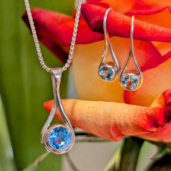 Photo of Blue Topaz "Desire" Pendant in a decorative scene, designed by , available at Plumb Gold & Plumb Silver