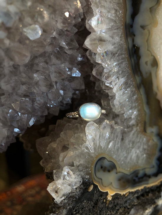 Photo of Blue Topaz over Mother of Pearl Ring in a decorative scene, designed by , available at Plumb Gold & Plumb Silver