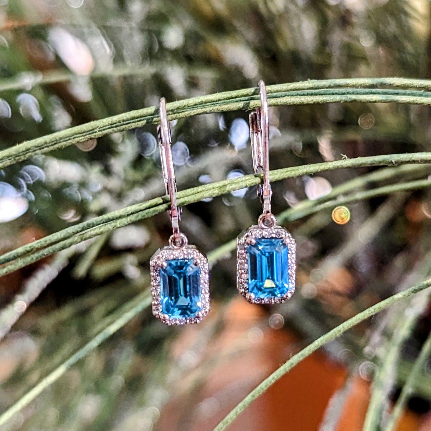 Photo of Blue Zircon Dangle Earrings in a decorative scene, designed by , available at Plumb Gold & Plumb Silver