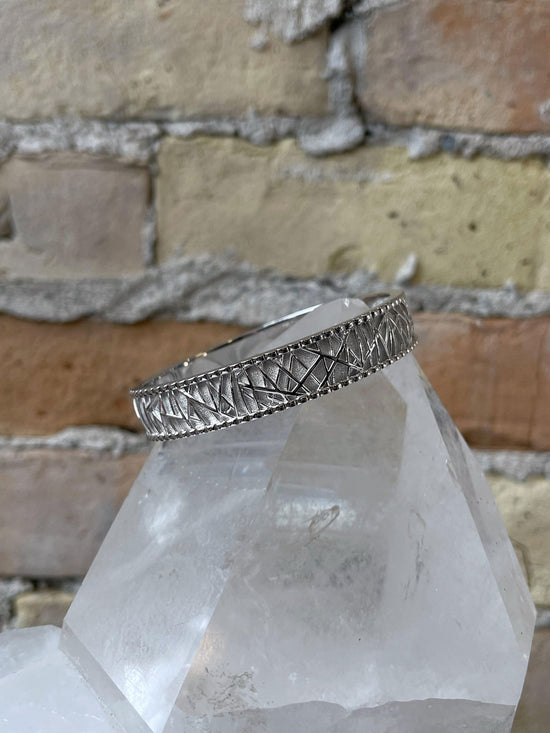 Photo of Breuning Textured Bangle in a decorative scene, designed by , available at Plumb Gold & Plumb Silver