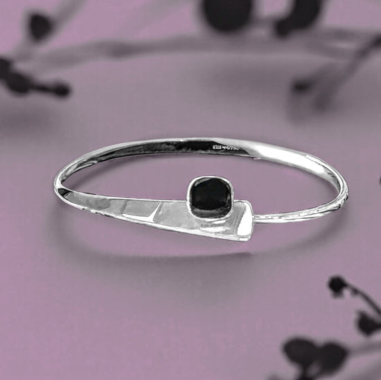 Photo of "Camber" Onyx Bracelet in a decorative scene, designed by , available at Plumb Gold & Plumb Silver