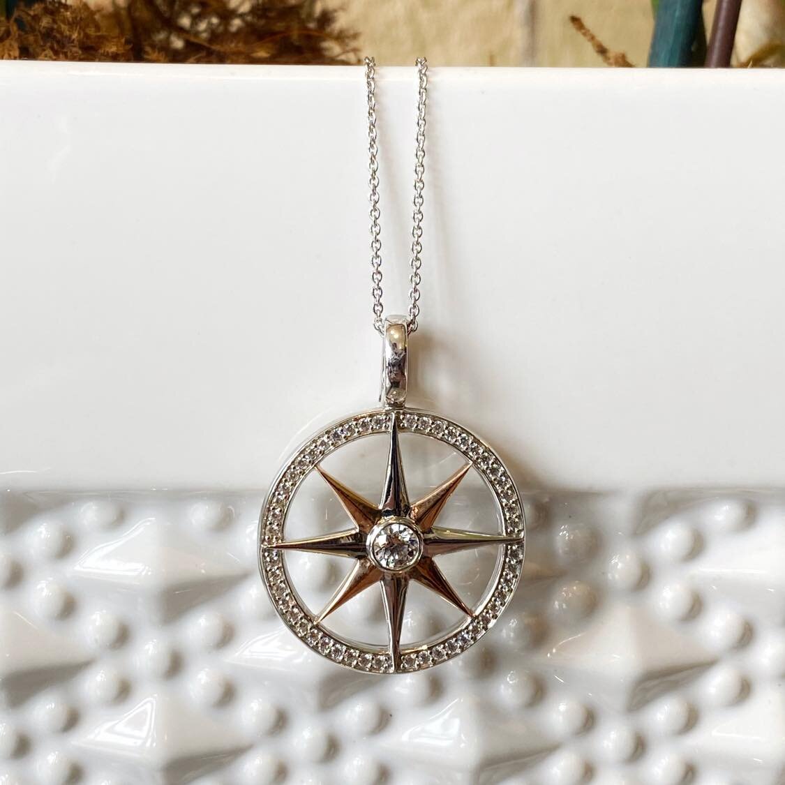 Photo of Compass Rose Pendant in a decorative scene, designed by , available at Plumb Gold & Plumb Silver