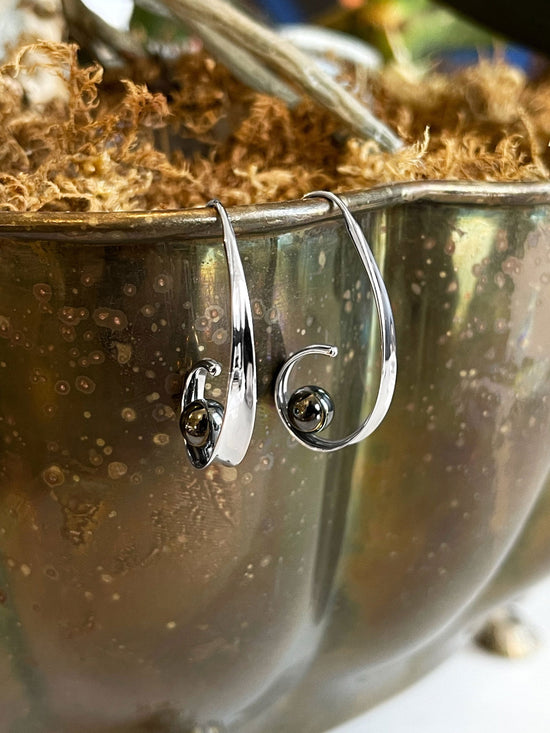 Photo of "Crosswind" Earrings in a decorative scene, designed by , available at Plumb Gold & Plumb Silver
