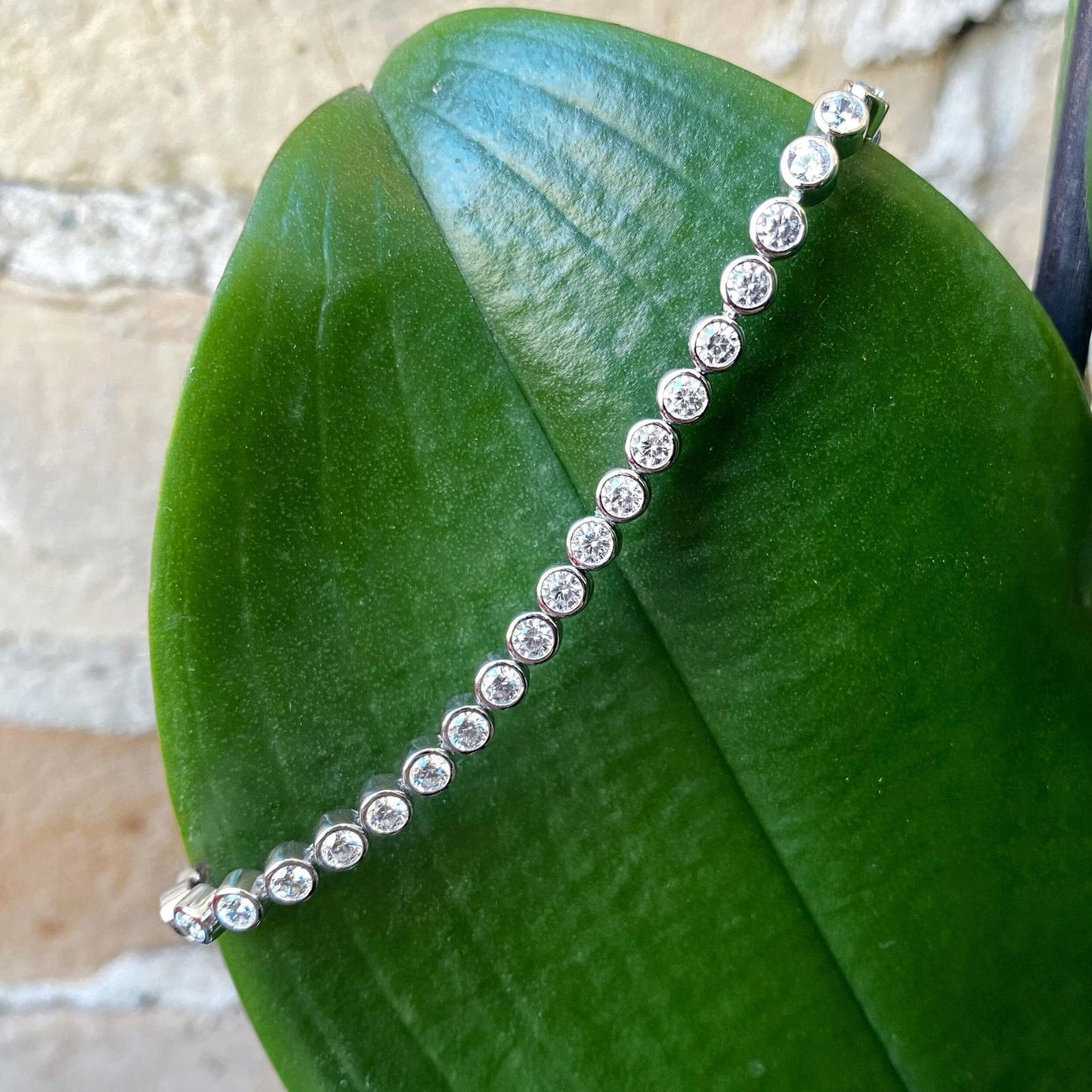 Photo of Cubic Zirconia Bezel Tennis Bracelet in a decorative scene, designed by , available at Plumb Gold & Plumb Silver