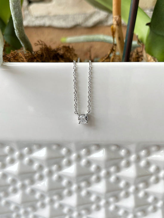 Photo of Cubic Zirconia Solitaire Necklace in a decorative scene, designed by , available at Plumb Gold & Plumb Silver