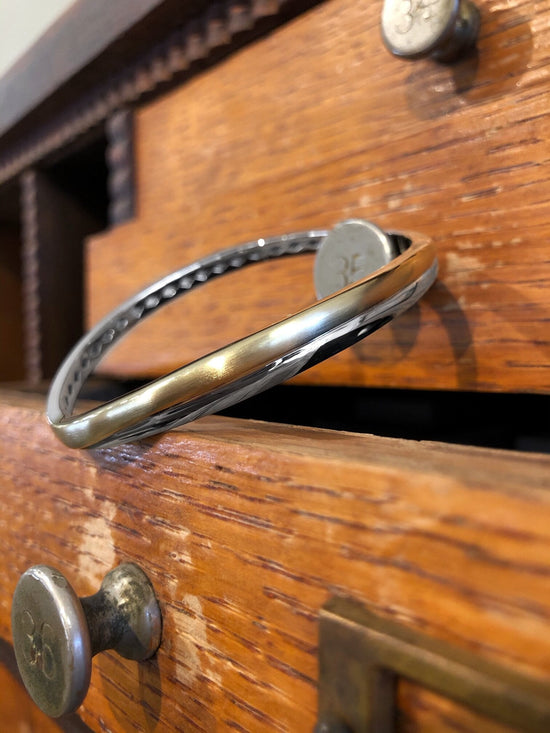 Photo of Curve Bangle Bracelet in a decorative scene, designed by , available at Plumb Gold & Plumb Silver