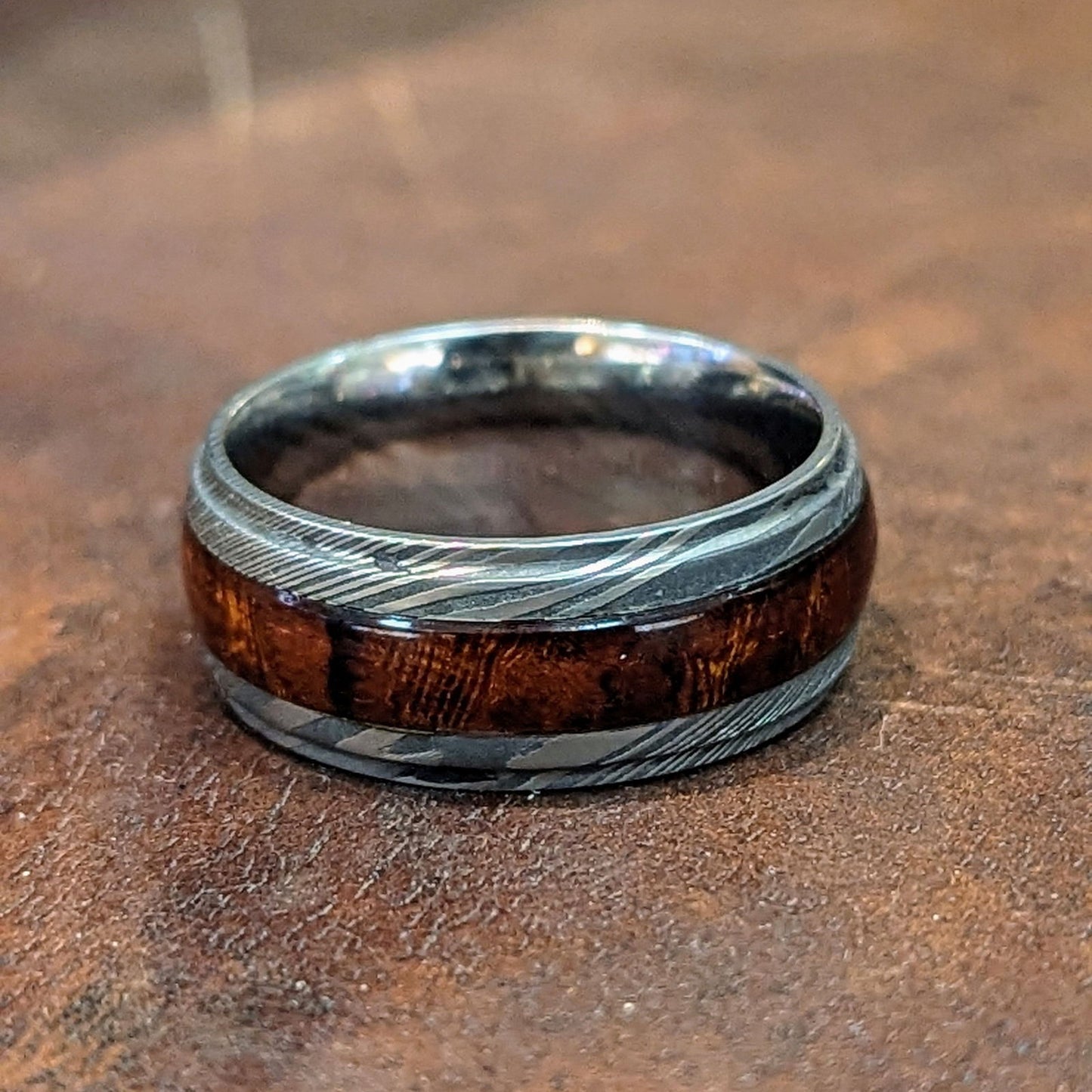 Photo of Damascus and Hardwood Band in a decorative scene, designed by , available at Plumb Gold & Plumb Silver