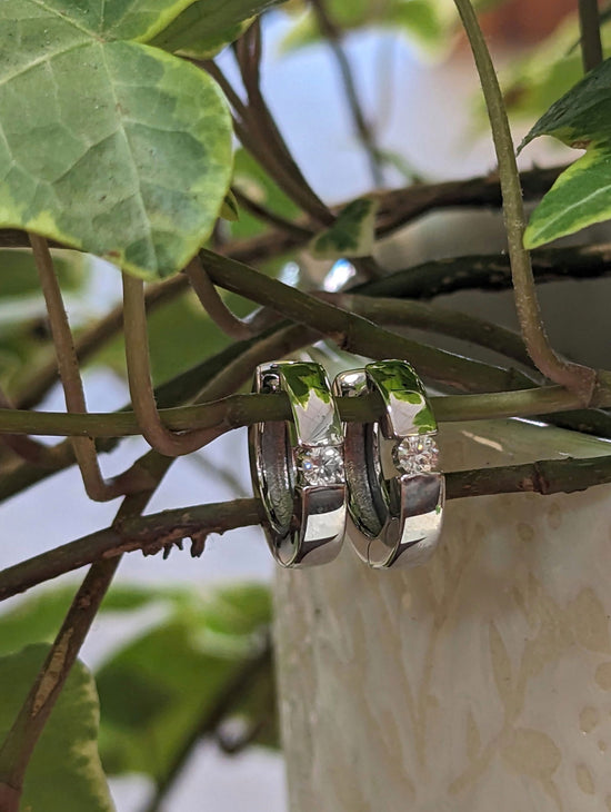 Photo of Diamond Accented Huggie Hoops in a decorative scene, designed by , available at Plumb Gold & Plumb Silver