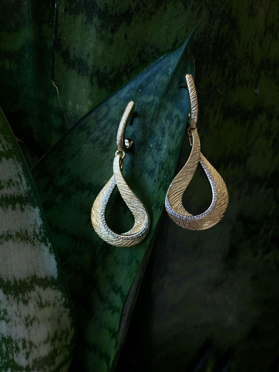 Photo of Diamond Cut Loop Dangle Earrings in a decorative scene, designed by , available at Plumb Gold & Plumb Silver
