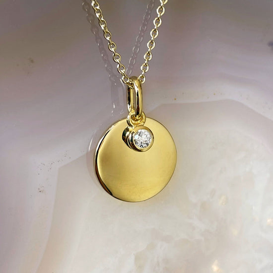 Photo of Diamond Disc Necklace in a decorative scene, designed by , available at Plumb Gold & Plumb Silver