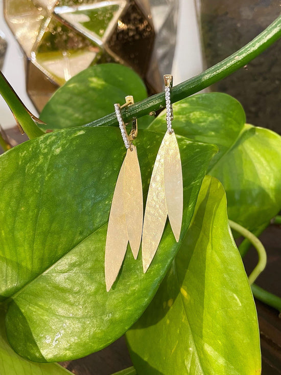 Photo of Diamond Leaf Earrings in a decorative scene, designed by , available at Plumb Gold & Plumb Silver
