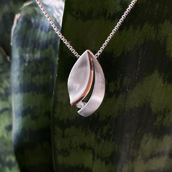 Photo of Diamond Leaf Pendant in a decorative scene, designed by , available at Plumb Gold & Plumb Silver