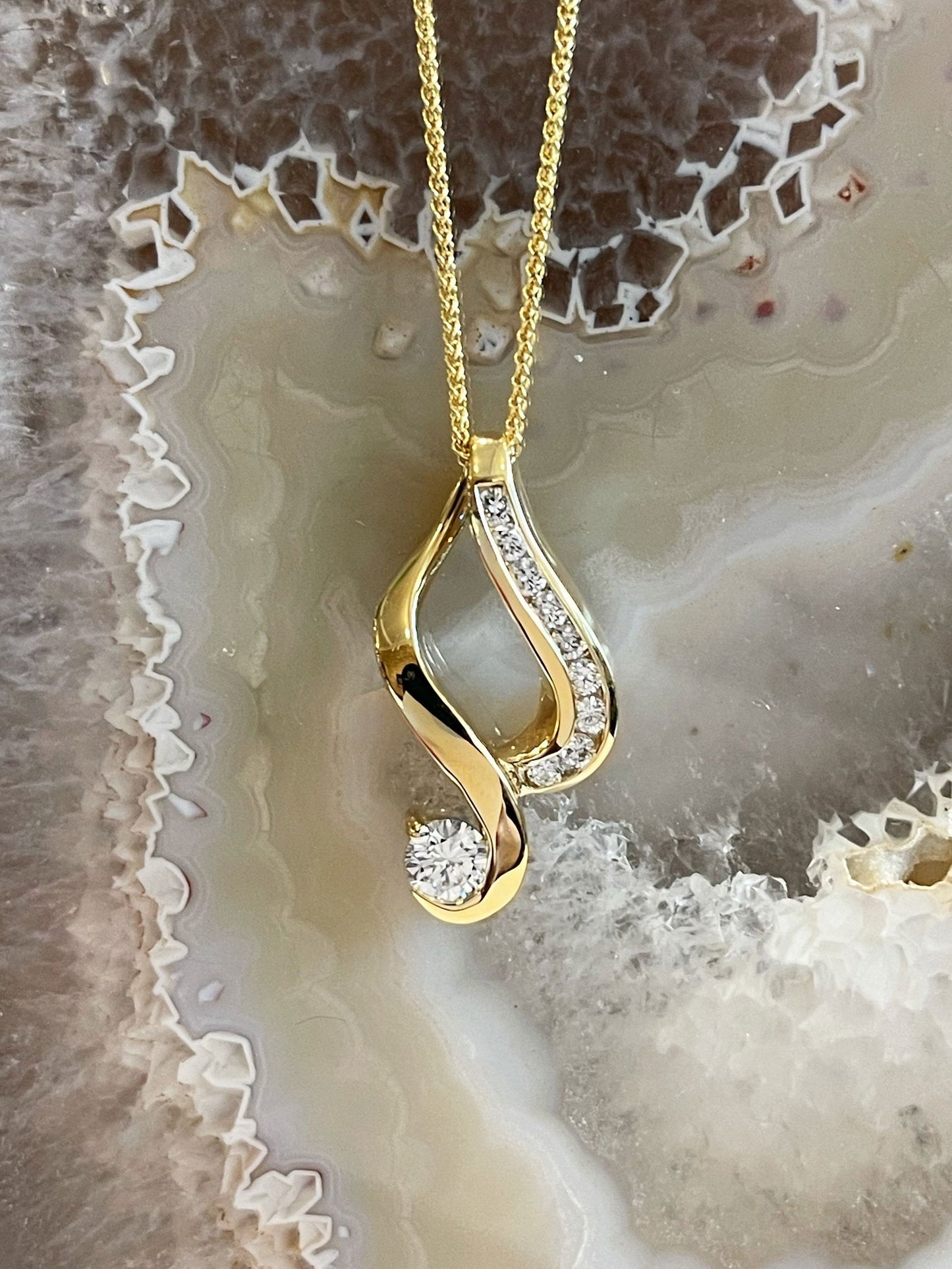 Photo of Diamond Swoosh Pendant in a decorative scene, designed by , available at Plumb Gold & Plumb Silver