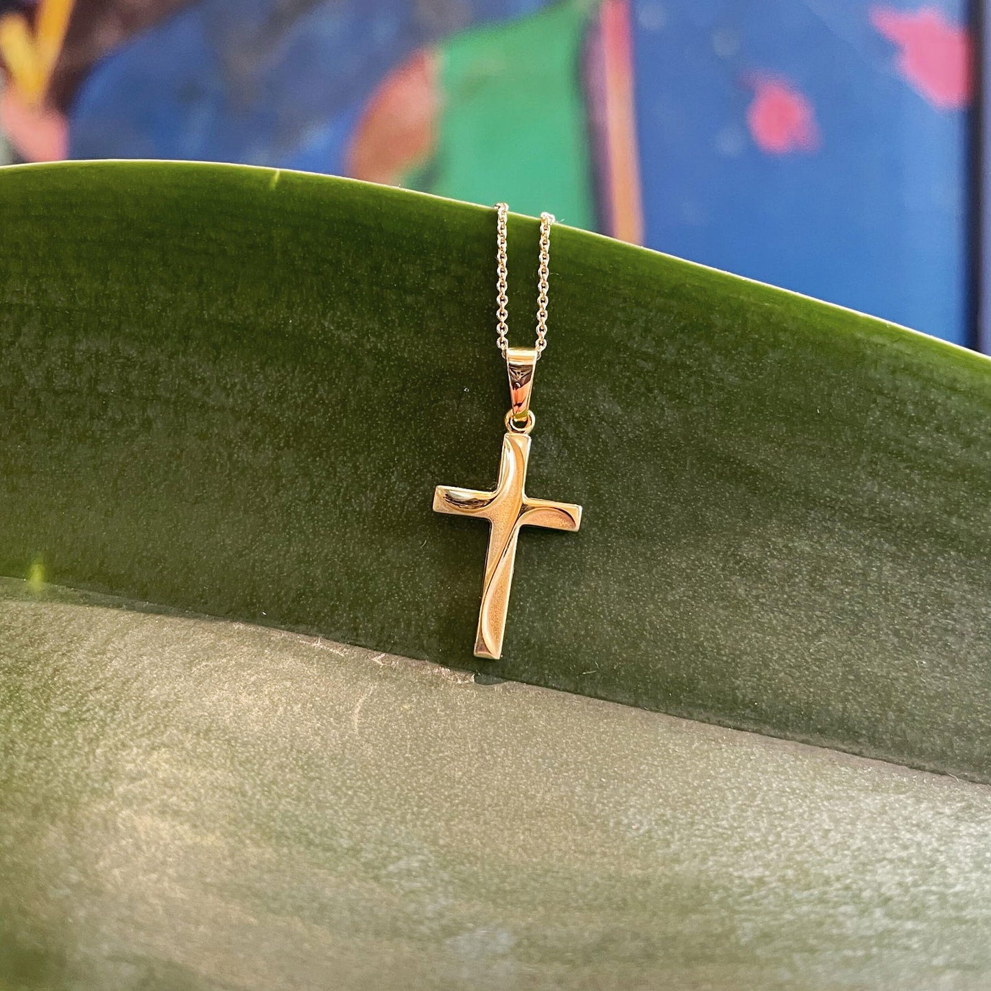 Photo of Draped Cross Necklace in a decorative scene, designed by , available at Plumb Gold & Plumb Silver