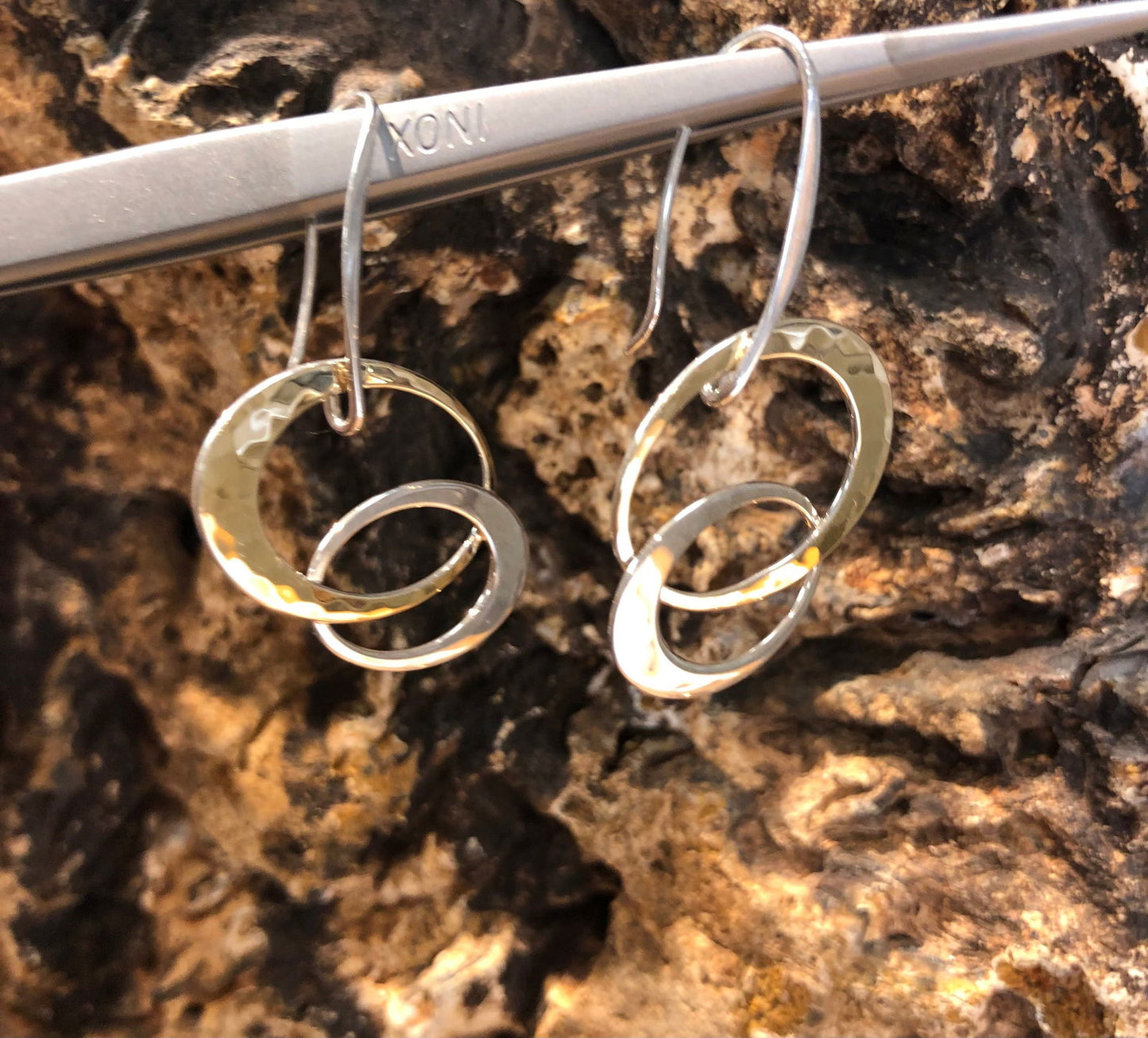 Photo of EL Designs "Entwined Elegance" Two-Toned Loop Earrings in a decorative scene, designed by , available at Plumb Gold & Plumb Silver