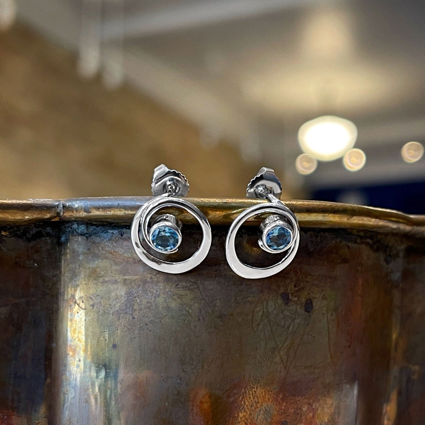 Photo of EL Designs "Posy" Blue Topaz Earrings in a decorative scene, designed by , available at Plumb Gold & Plumb Silver