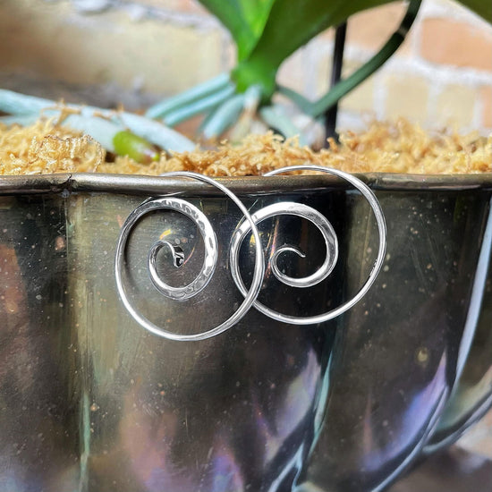 Photo of E L Designs "Crop Circle" Spiral Sterling Silver Hoop Earrings in a decorative scene, designed by , available at Plumb Gold & Plumb Silver