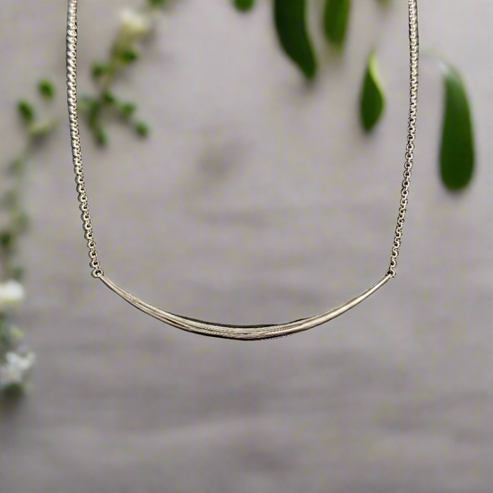 Photo of "Eclipse" Necklace in a decorative scene, designed by , available at Plumb Gold & Plumb Silver