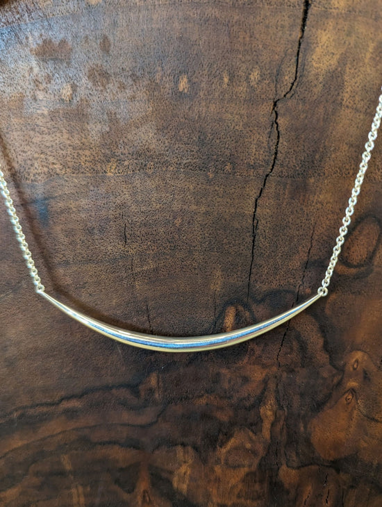 Photo of "Eclipse" Necklace in a decorative scene, designed by , available at Plumb Gold & Plumb Silver