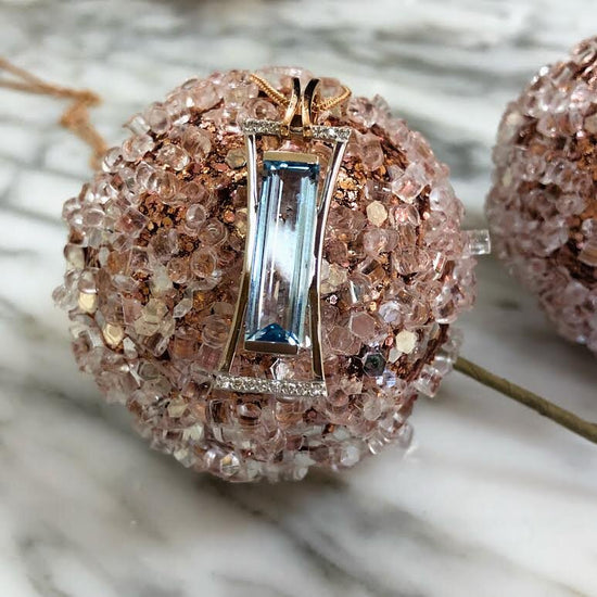 Photo of Elongated Blue Topaz Pendant in a decorative scene, designed by , available at Plumb Gold & Plumb Silver