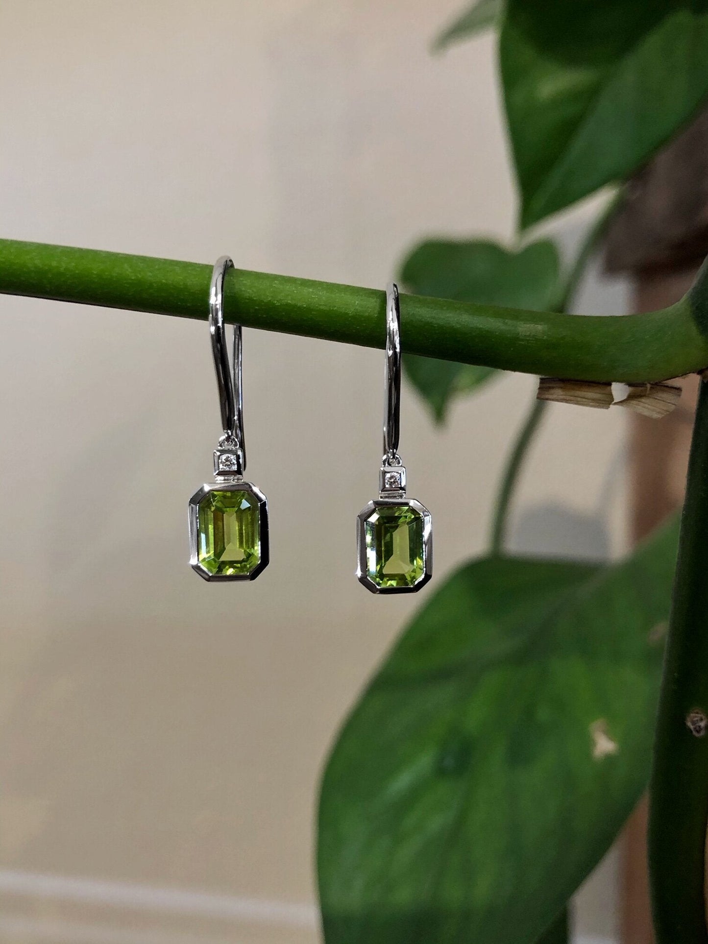 Photo of Emerald-Cut Peridot and Diamond Dangles in a decorative scene, designed by , available at Plumb Gold & Plumb Silver