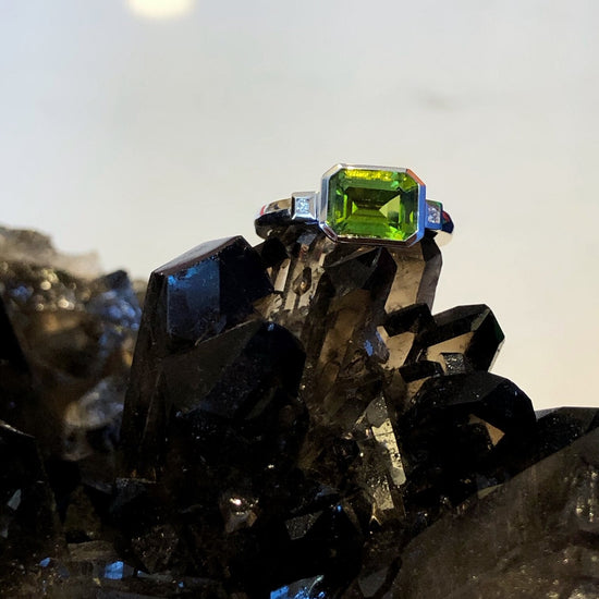 Photo of Emerald-Cut Peridot and Diamond Ring in a decorative scene, designed by , available at Plumb Gold & Plumb Silver