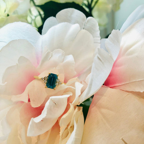 Photo of Emerald Cut Blue Zircon Diamond Ring in a decorative scene, designed by , available at Plumb Gold & Plumb Silver