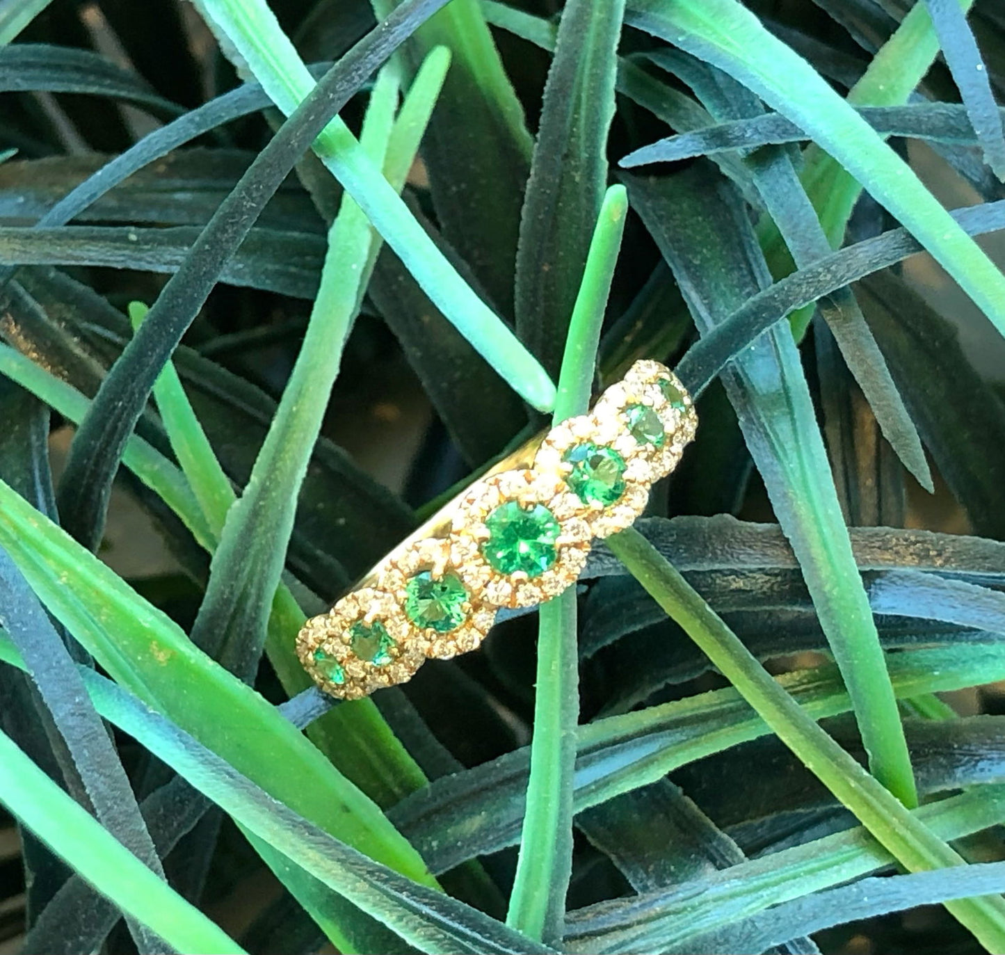Photo of Emerald Seven Halo Ring in a decorative scene, designed by , available at Plumb Gold & Plumb Silver