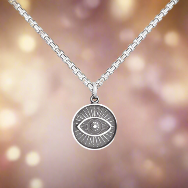 Photo of Evil Eye Oxidized Silver Pendant in a decorative scene, designed by , available at Plumb Gold & Plumb Silver