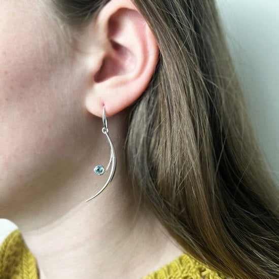 Photo of "Featherstone" Blue Topaz Earrings in a decorative scene, designed by , available at Plumb Gold & Plumb Silver