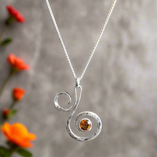 Photo of "Fiddlehead" Necklace in a decorative scene, designed by , available at Plumb Gold & Plumb Silver