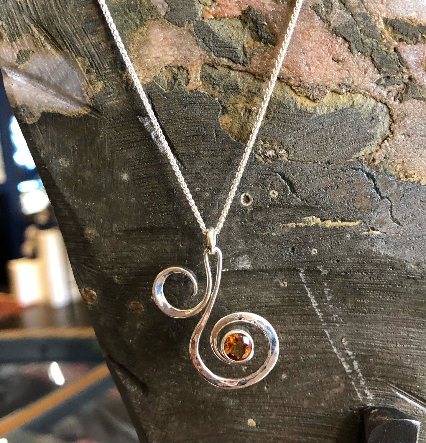 Photo of "Fiddlehead" Necklace in a decorative scene, designed by , available at Plumb Gold & Plumb Silver