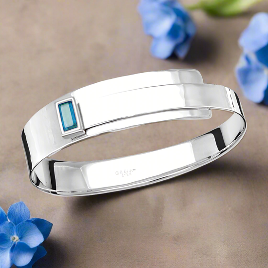 Photo of "Fifth Ave" Bangle in a decorative scene, designed by , available at Plumb Gold & Plumb Silver
