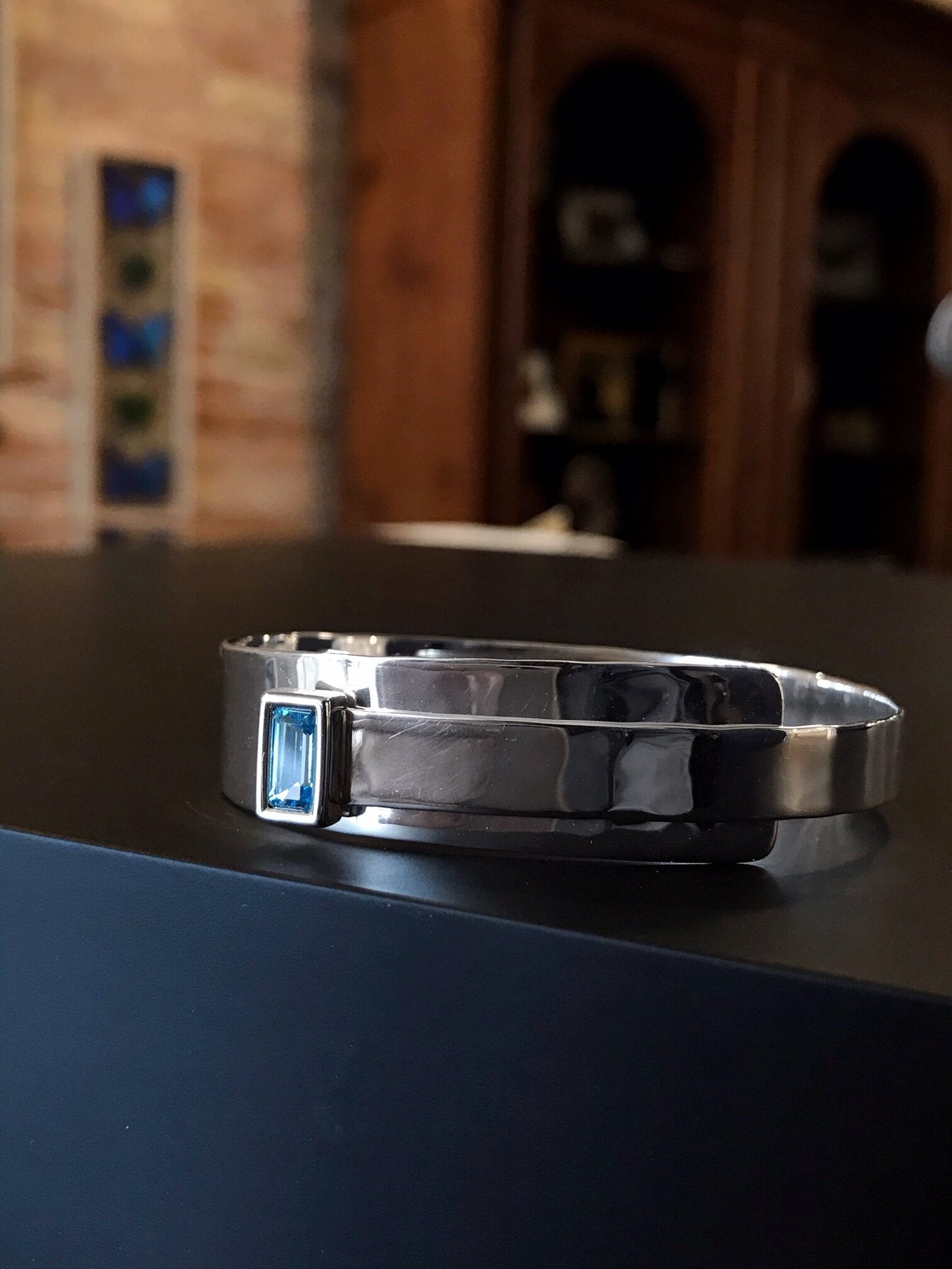 Photo of "Fifth Ave" Bangle in a decorative scene, designed by , available at Plumb Gold & Plumb Silver