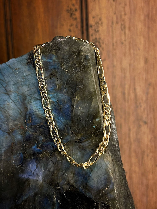 Photo of Figaro Bracelet in a decorative scene, designed by , available at Plumb Gold & Plumb Silver
