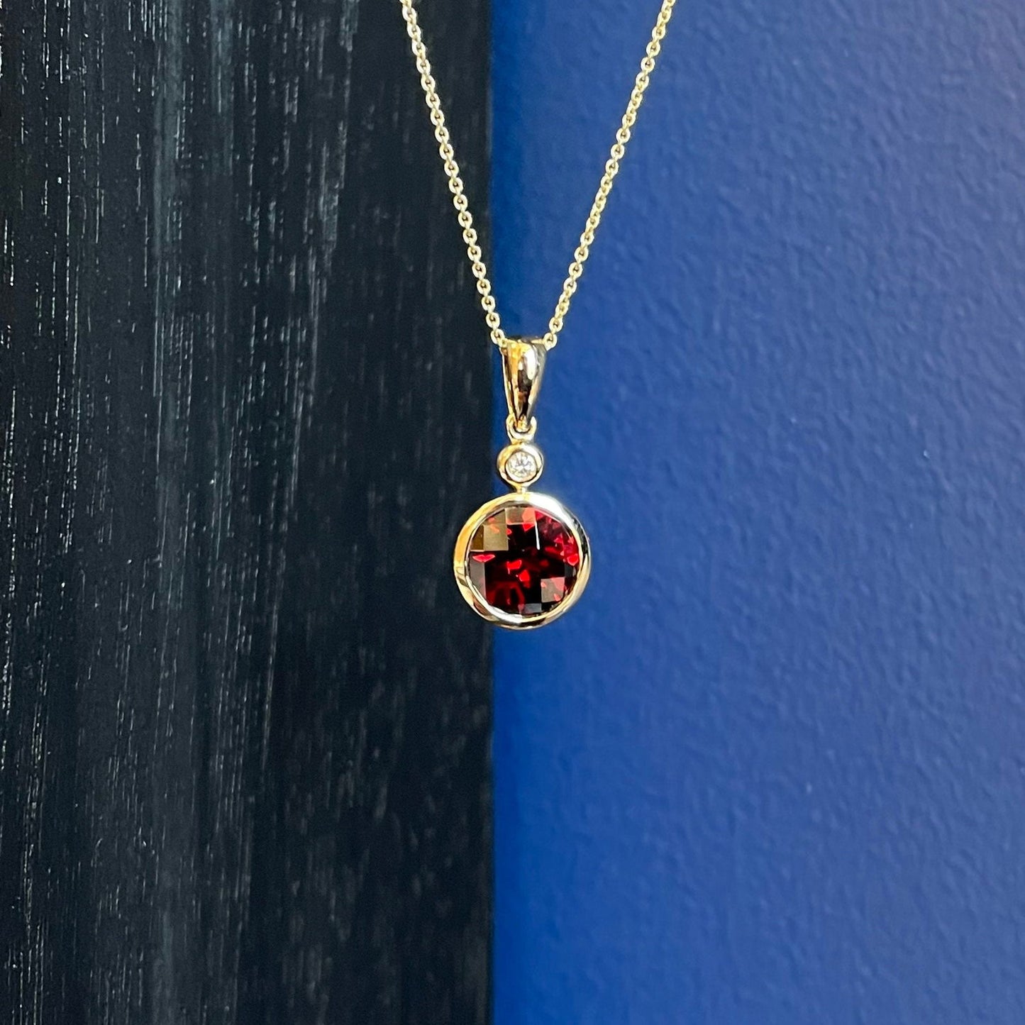 Photo of Garnet and Diamond Pendant in a decorative scene, designed by , available at Plumb Gold & Plumb Silver