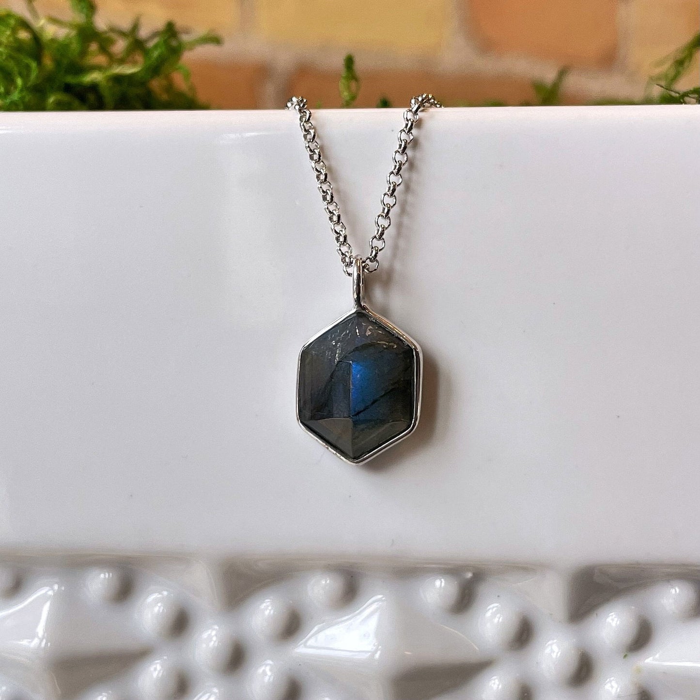 Photo of “Geo” Labradorite Pendant in a decorative scene, designed by , available at Plumb Gold & Plumb Silver