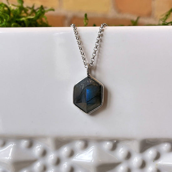 Photo of “Geo” Labradorite Pendant in a decorative scene, designed by , available at Plumb Gold & Plumb Silver