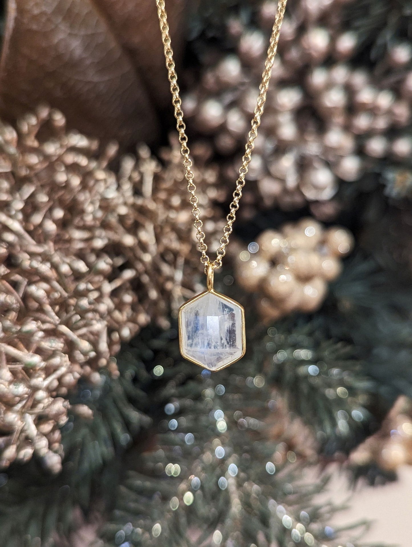 Photo of "Geo" Moonstone Pendant in a decorative scene, designed by , available at Plumb Gold & Plumb Silver