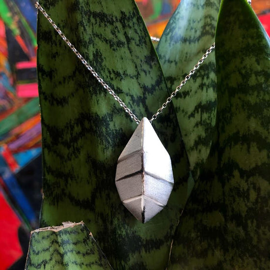 Photo of "Geometric" Leaf Pendant in a decorative scene, designed by , available at Plumb Gold & Plumb Silver
