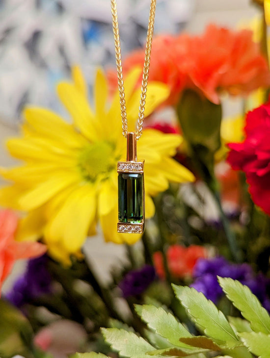 Photo of Green Tourmaline Bar Pendant in a decorative scene, designed by , available at Plumb Gold & Plumb Silver