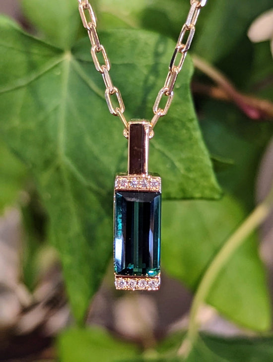 Photo of Green Tourmaline Bar Pendant in a decorative scene, designed by , available at Plumb Gold & Plumb Silver